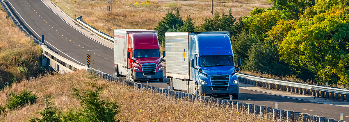 Crete and Shaffer trucks travel in tandem on a highway in the central Nebraska Sandhills.